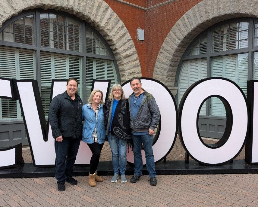 RJ, Jaime, me and Derek in front of six-foot white letters the spell CWOOD