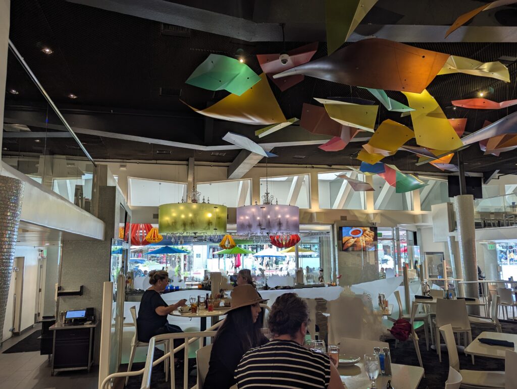 Inside a restaurant called Lulus with sculptures and huge chandeliers in all sorts of fun colours like purple, yellow, and orange. 